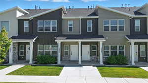 Multi unit property with board and batten siding, stone siding, a shingled roof, and a front lawn