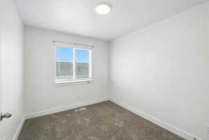 Empty room with baseboards and dark carpet