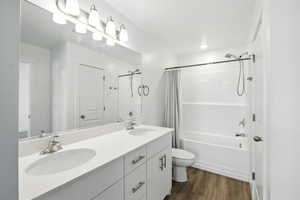 Full bath featuring shower / bath combo, double vanity, and wood finished floors