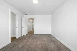 Carpeted spare room featuring baseboards