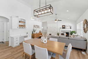 Dining room with a ceiling fan, a fireplace, light wood-style flooring, arched walkways, and recessed lighting