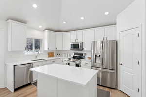 Kitchen featuring stainless steel appliances, white cabinets, light wood-style floors, recessed lighting, and a kitchen island