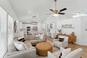 Living area with light wood-type flooring, ceiling fan, high vaulted ceiling, recessed lighting, and a skylight