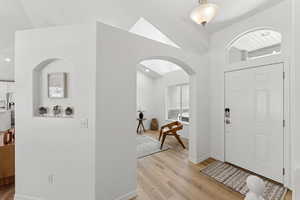 Foyer with arched walkways, light wood-type flooring, and recessed lighting