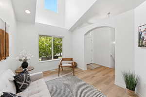 Sitting room featuring arched walkways, light wood-type flooring, a towering ceiling, and recessed lighting