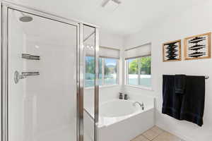 Bathroom featuring a garden tub, a shower stall, and tile patterned floors