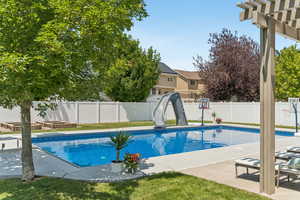 View of pool with a water slide, a fenced backyard, and a patio area