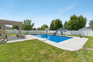 View of pool featuring a water slide, a patio area, a diving board, and a fenced backyard