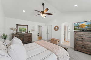 Bedroom with lofted ceiling, arched walkways, ensuite bath, recessed lighting, and ceiling fan