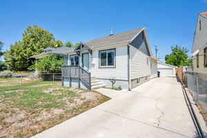 Bungalow-style house with a garage, an outbuilding, and a shingled roof