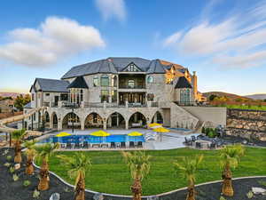 Rear view of property featuring a high end roof, a hot tub, an outdoor pool, a balcony, and a patio