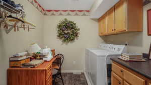 Washroom featuring washer and dryer, cabinet space, dark marble finish floors, and a desk