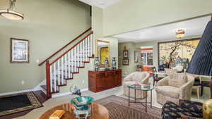 Living area featuring stairs, carpet flooring, and a high ceiling