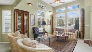 Living area with ceiling fan, carpet flooring, and a high ceiling