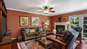 Living room with ceiling fan, hardwood / wood-style flooring, a high end fireplace, and crown molding