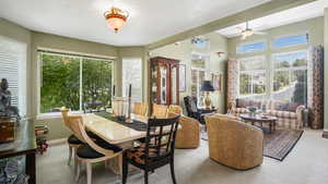 Dining space featuring healthy amount of natural light, light colored carpet, and a ceiling fan