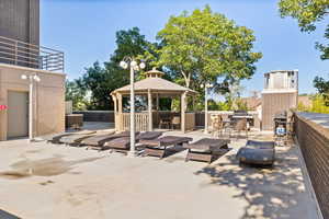 View of patio featuring a gazebo, a grill, and an outdoor brick fireplace