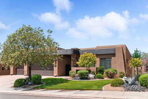 View of front of home with an attached garage, driveway, a front yard, and stucco siding