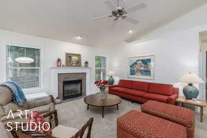 Carpeted living room featuring lofted ceiling, a ceiling fan, and a fireplace