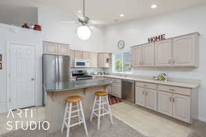 Kitchen featuring stainless steel appliances, high vaulted ceiling, a breakfast bar, ceiling fan, and a center island