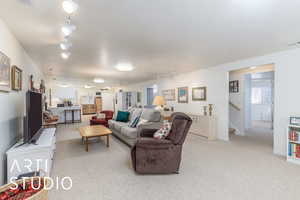 Living room featuring track lighting, light carpet, and stairs