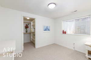 Unfurnished bedroom featuring carpet and a walk in closet