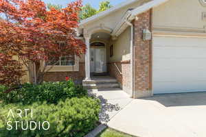 Property entrance featuring brick siding, an attached garage, and stucco siding