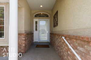 Entrance to property with stucco siding and brick siding