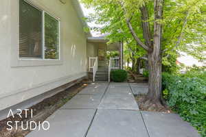 View of exterior entry with stucco siding, patio and deck.