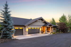 Craftsman house featuring stone siding, an attached garage, driveway, covered porch, and a shingled roof