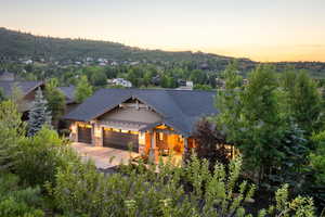 Craftsman-style house with stone siding, a garage, roof with shingles, and driveway