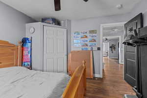 Bedroom with a textured ceiling, a closet, dark wood-style flooring, and ceiling fan