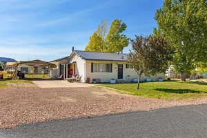 Ranch-style house featuring a metal roof, a detached carport, a front lawn, and driveway