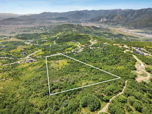 Aerial overview of property's location with property parcel outlined and a mountainous background