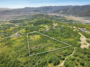 Aerial overview of property's location with property parcel outlined and a mountainous background