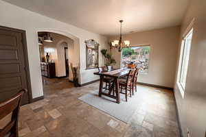 Dining room with stone tile floors, arched walkways, and a chandelier