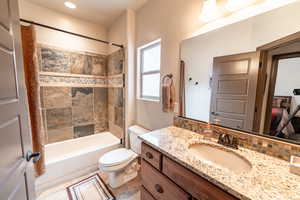 Bathroom with vanity, shower / bath combo, and decorative backsplash
