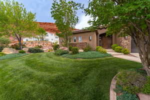 View of front of property with stone siding, stucco siding, a front yard, and a tiled roof