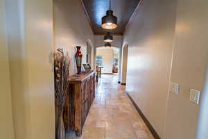 Hall with stone tile flooring, ornamental molding, and arched walkways