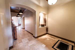 Hallway featuring stone tile flooring, arched walkways, and a high ceiling