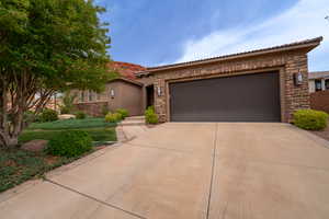 View of front of house with stone siding, concrete driveway, and a garage