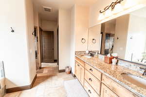 Bathroom featuring stone tile flooring and double vanity