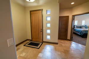 Foyer entrance with stone tile flooring and recessed lighting