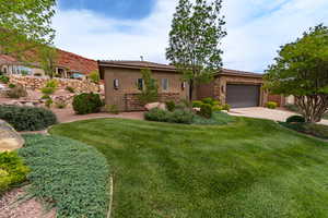 Mediterranean / spanish-style house with stucco siding, stone siding, driveway, an attached garage, and a front lawn