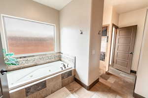 Bathroom with a tub with jets and stone tile flooring