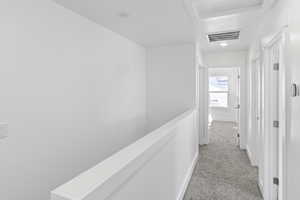 Hallway featuring light colored carpet and attic access
