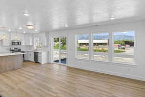 Kitchen featuring appliances with stainless steel finishes, light countertops, light wood-style floors, recessed lighting, and a textured ceiling