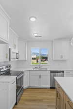 Kitchen featuring stainless steel appliances, light countertops, white cabinets, a textured ceiling, and recessed lighting