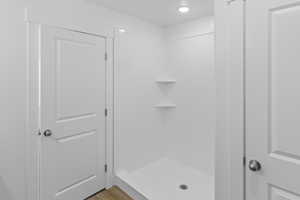 Full bath featuring a shower stall and wood finished floors