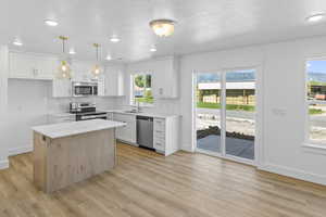 Kitchen with appliances with stainless steel finishes, backsplash, light wood-style floors, light countertops, and white cabinets